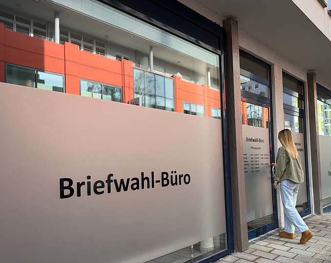 Junge Frau an der Eingangstür zum Briefwahl-Büro
