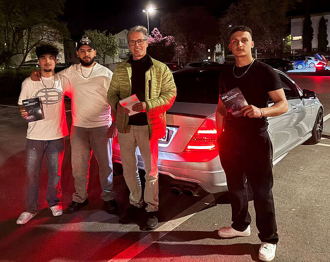 Vier Männer stehen vor einem weißen Auto.