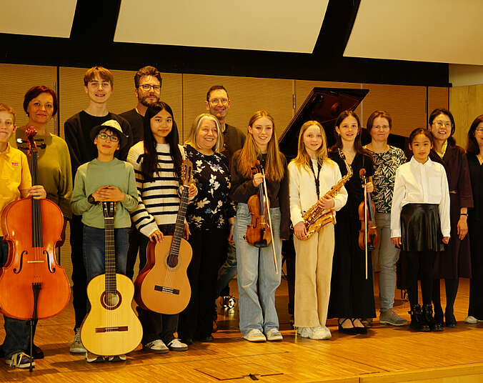 Kinder und Erwachsene mit Instrumenten auf der Bühne stehend.