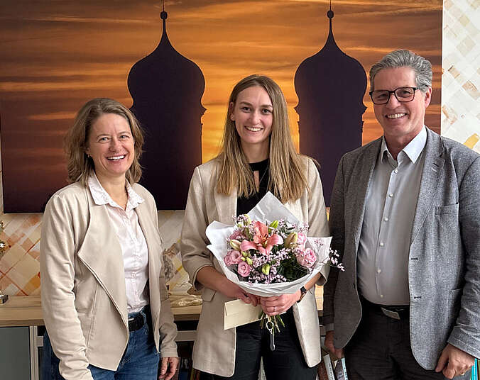 Zwei Frauen und ein Mann, eine Frau hält Strauß in den Händen