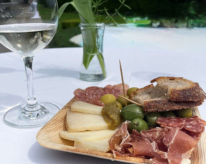 Teller mit Snacks und ein Glas Wein stehen auf einem Tisch