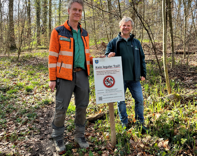 Zwei Männer mit Schild im Wald.